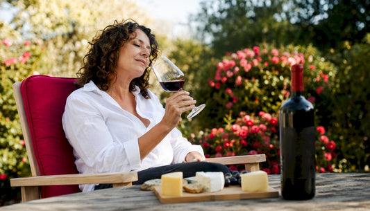 Woman tasting red wine at home table