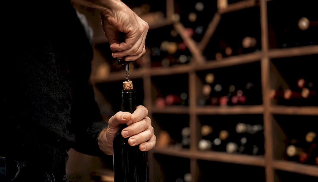 Hand uncorking wine bottle in cellar